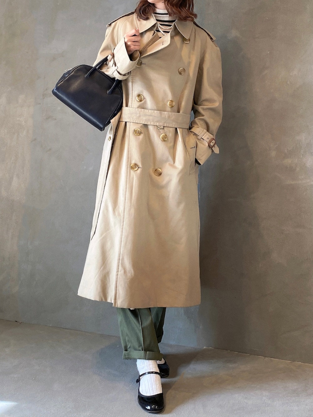 グリーン系のパンツ、ホワイト系のトップス、ベージュ系のトレンチコートを着用したレディースの冬コーディネートの3枚目の写真