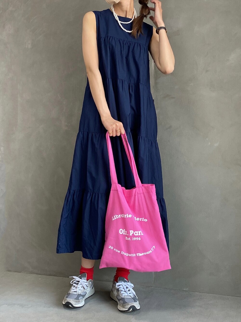 ピンク系のバッグ、グレー系のスニーカー、ブルー系のワンピースを着用したレディースの夏コーディネートの3枚目の写真