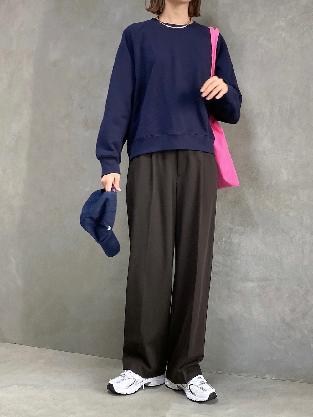 ブラック系のスウェット、ホワイト系のスニーカー、ブラウン系のスラックスを着用したレディースの秋コーディネートの2枚目の写真