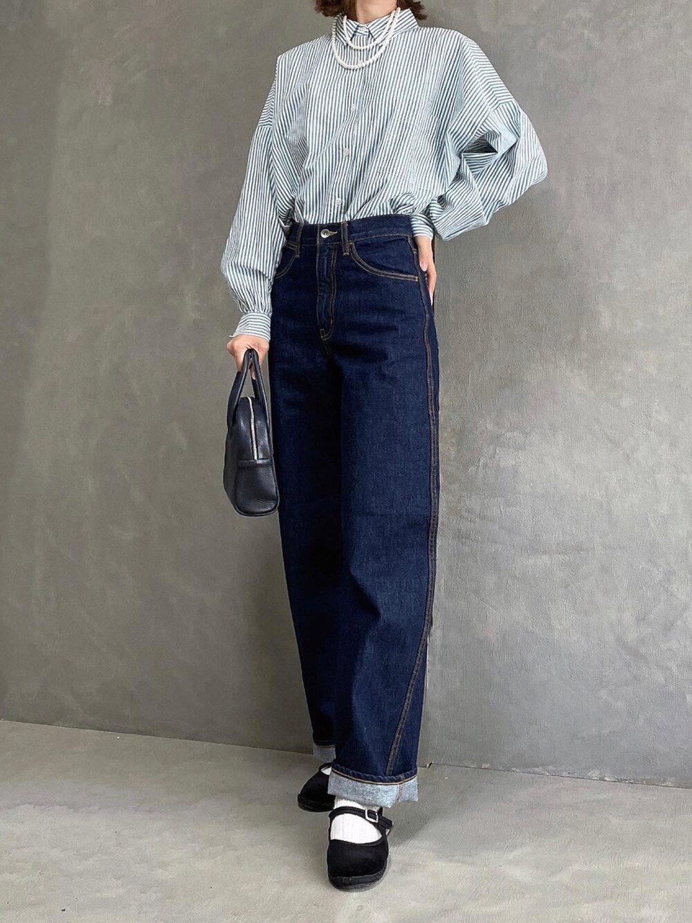 ブラック系のボストンバッグ、ブラック系のその他シューズ、ブルー系のデニムパンツを着用したレディースの秋コーディネートの2枚目の写真