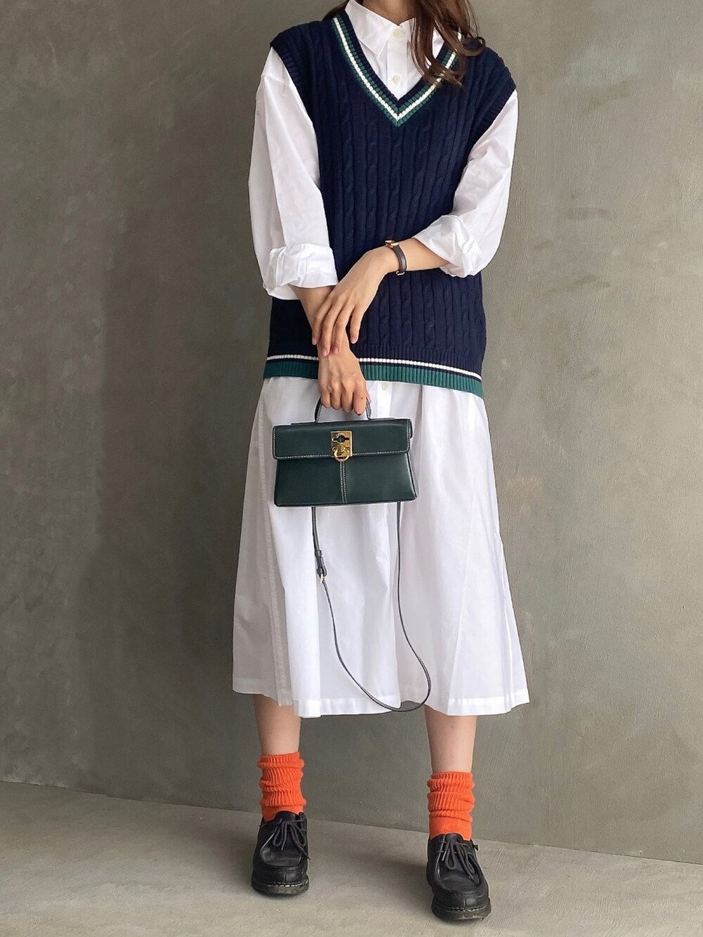 ブラック系のベスト、ホワイト系のワンピース/ドレス、グリーン系のバッグを着用したレディースの秋コーディネートの2枚目の写真