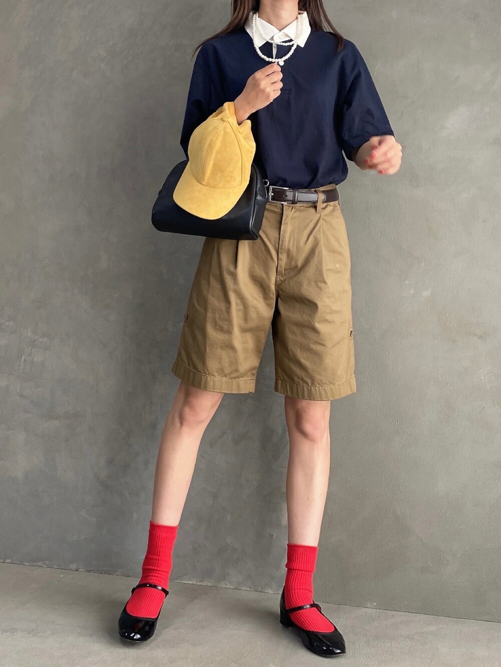 ブルー系のポロシャツ、ブラック系のボストンバッグ、ベージュ系のパンツを着用したレディースの夏コーディネートの4枚目の写真