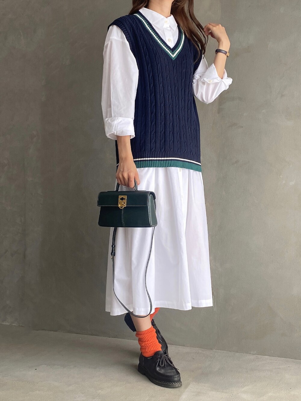 ブラック系のベスト、ホワイト系のワンピース/ドレス、グリーン系のバッグを着用したレディースの秋コーディネートの3枚目の写真