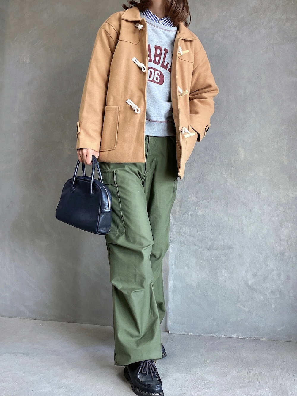 ブラック系のドレスシューズ、ブラック系のボストンバッグ、グレー系のスウェットを着用したレディースの冬コーディネートの2枚目の写真