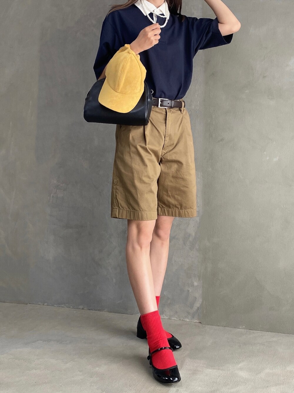 ブルー系のポロシャツ、ブラック系のボストンバッグ、ベージュ系のパンツを着用したレディースの夏コーディネートの2枚目の写真