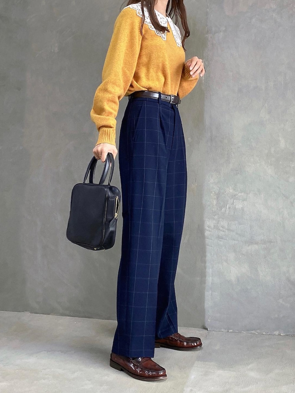 ブラック系のハンドバッグ、オレンジ系のニット/セーター、ブルー系のスラックスを着用したレディースの秋コーディネートの2枚目の写真