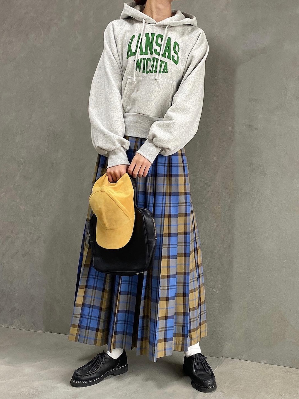 ブルー系のスカート、グレー系のパーカー、ブラック系のドレスシューズを着用したレディースの春コーディネートの2枚目の写真