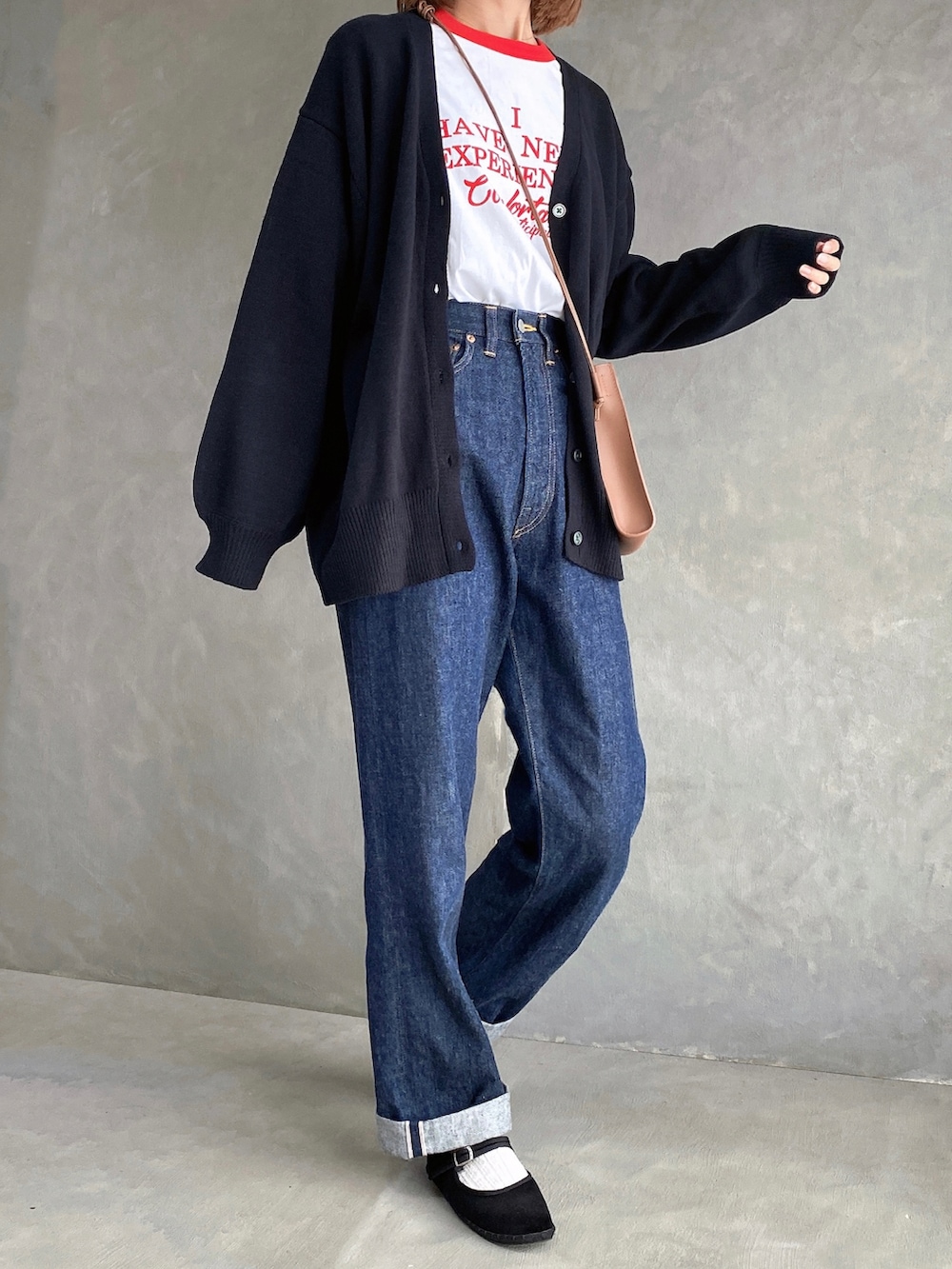 レッド系のTシャツ/カットソー、ブラウン系のショルダーバッグ、ブルー系のデニムパンツを着用したレディースの秋コーディネートの2枚目の写真