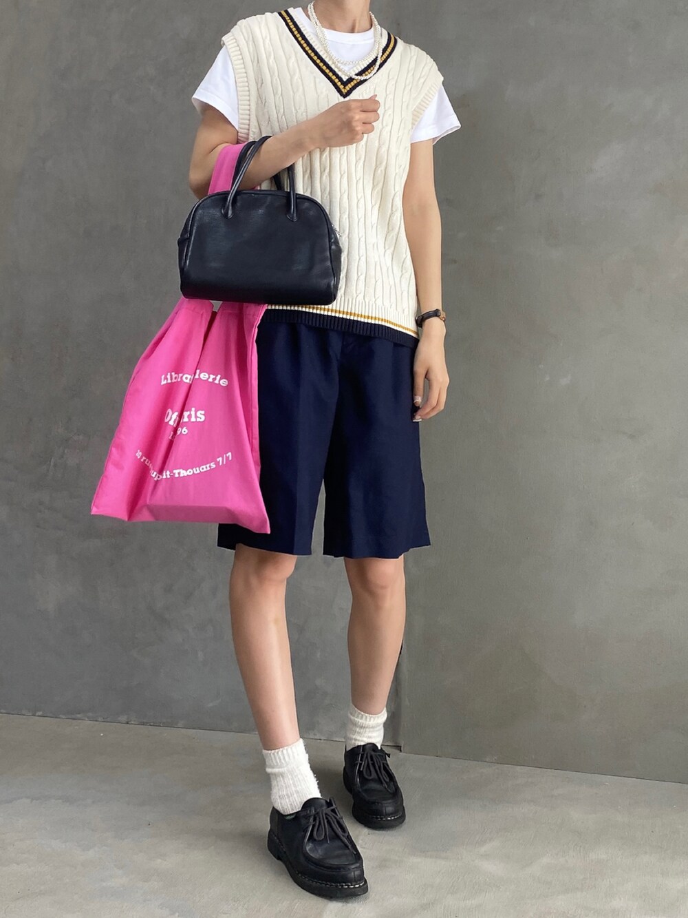 ブラック系のパンツ、ピンク系のバッグ、ブラック系のドレスシューズを着用したレディースの夏コーディネートの2枚目の写真