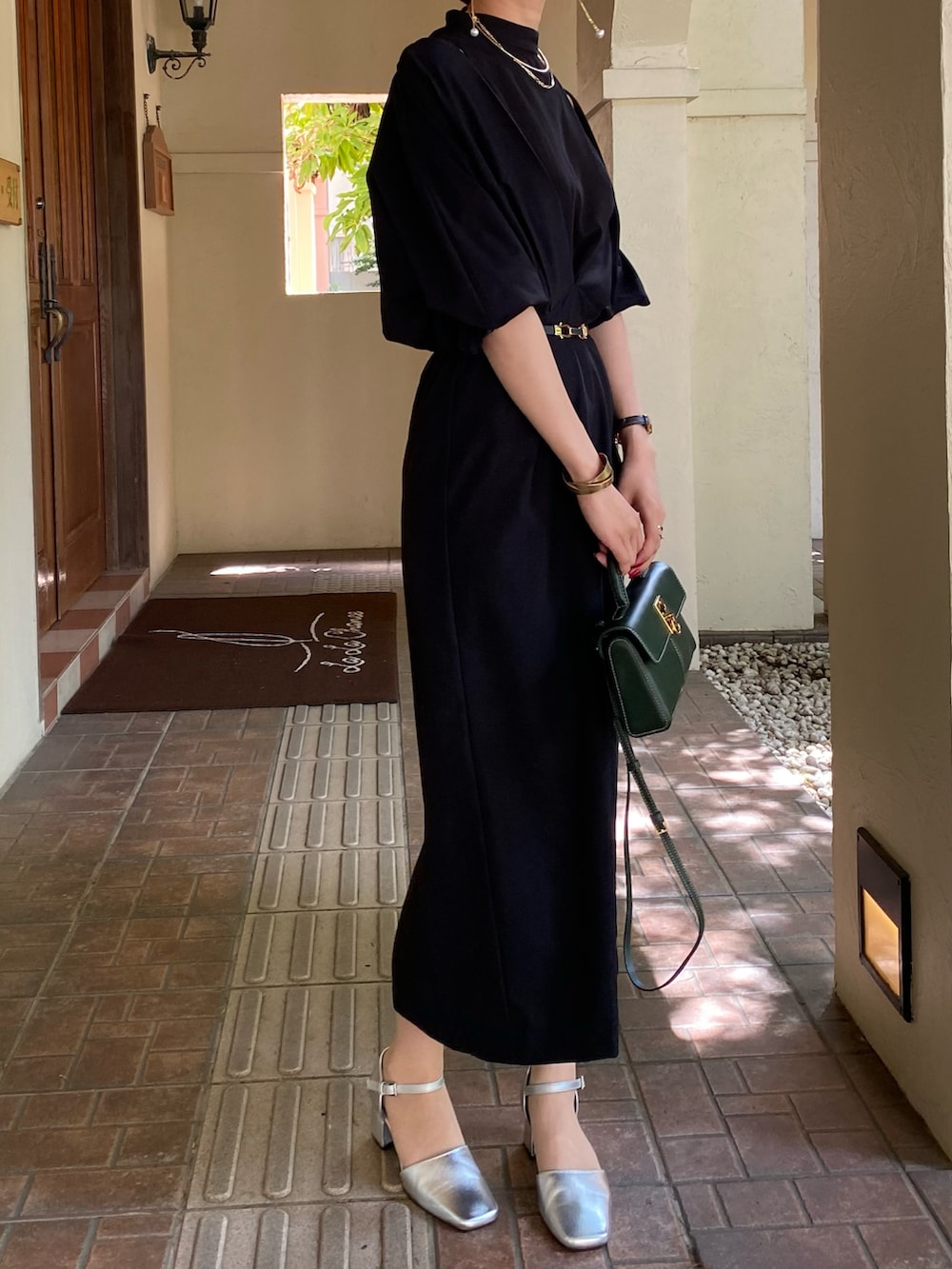 ブラック系のワンピース、シルバー系のパンプス、グリーン系のバッグを着用したレディースの夏コーディネートの2枚目の写真