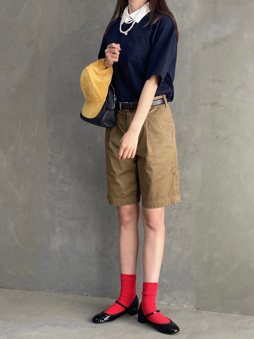 ブルー系のポロシャツ、ブラック系のボストンバッグ、ベージュ系のパンツを着用したレディースの夏コーディネートの3枚目の写真