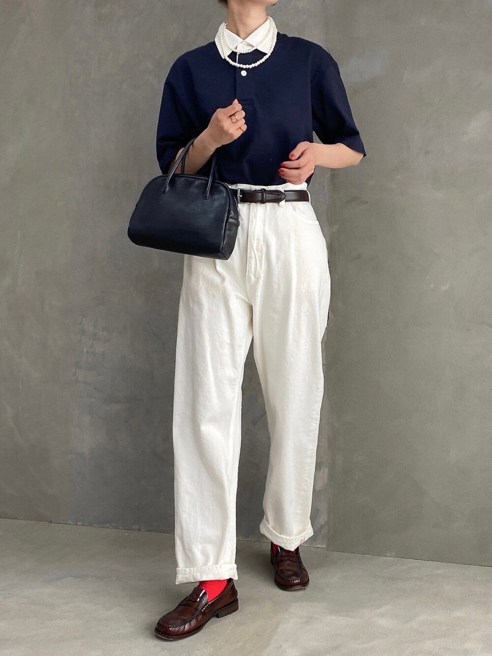 ブルー系のポロシャツ、ブラック系のボストンバッグ、ホワイト系のデニムパンツを着用したレディースの春コーディネートの3枚目の写真