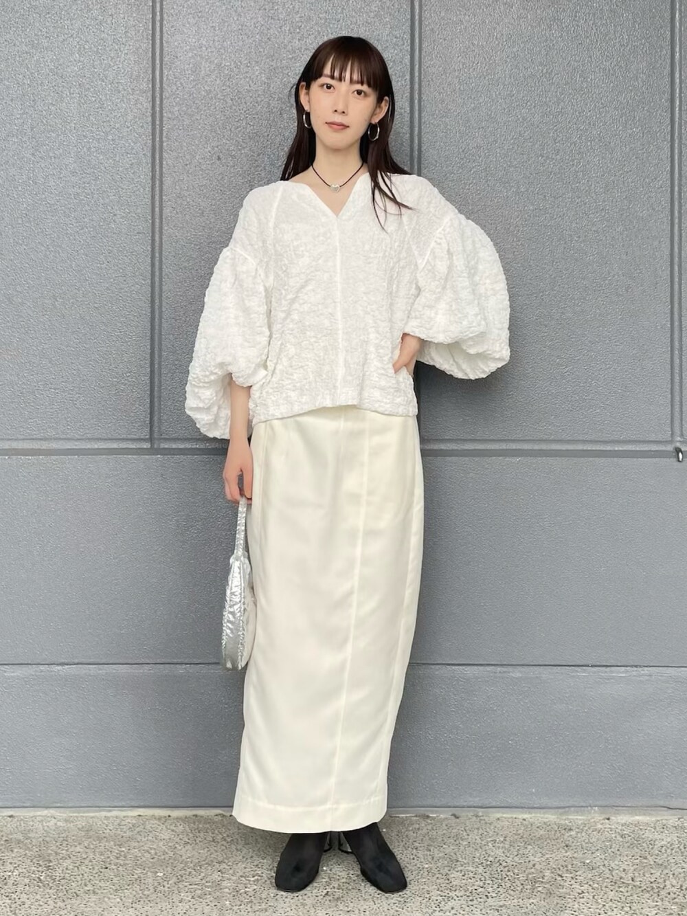 ホワイト系のシャツ/ブラウス、ホワイト系のスカート、ブラック系のブーツを着用したレディースの春コーディネートの2枚目の写真