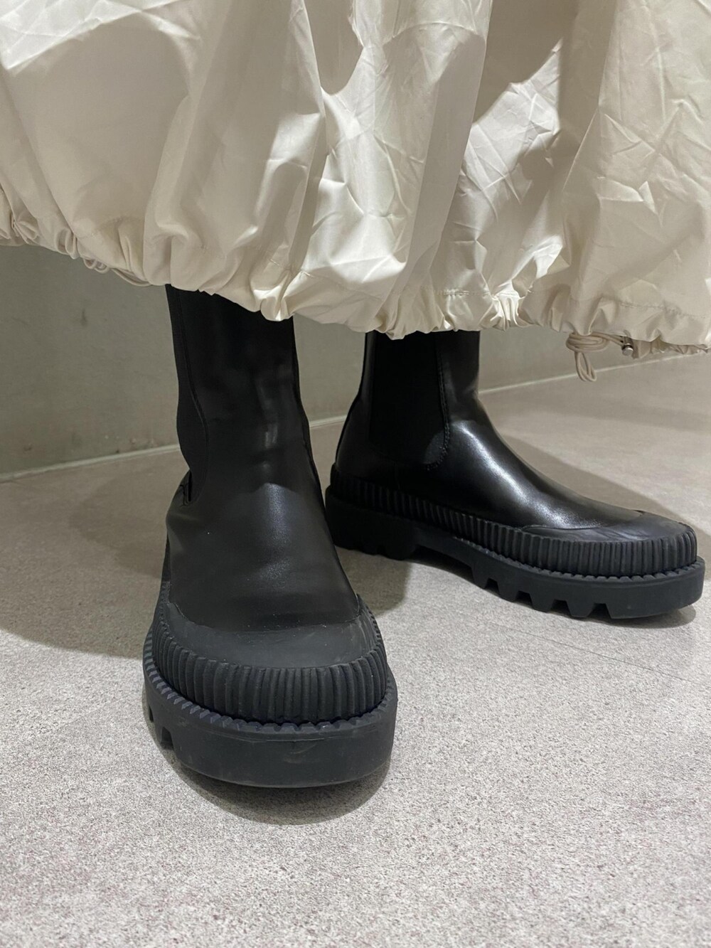 ホワイト系のワンピース、ブラック系のショルダーバッグ、ブラック系のブーツを着用したレディースの夏コーディネートの4枚目の写真