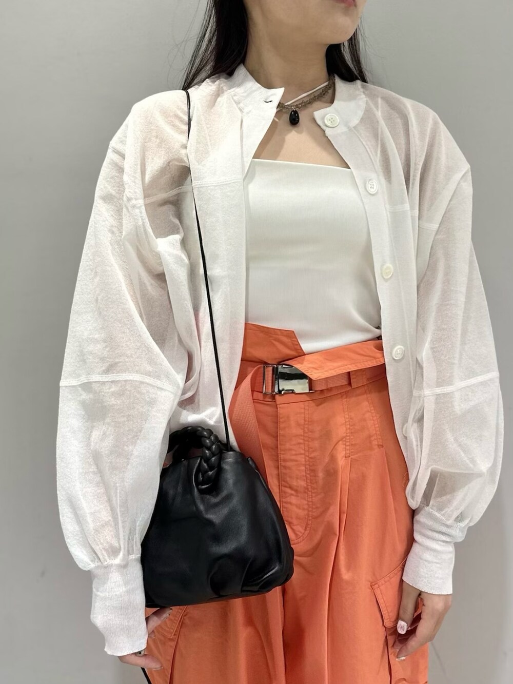 ホワイト系のカーディガン/ボレロ、オレンジ系のカーゴパンツ、ホワイト系のキャミソールを着用したレディースの春コーディネートの5枚目の写真