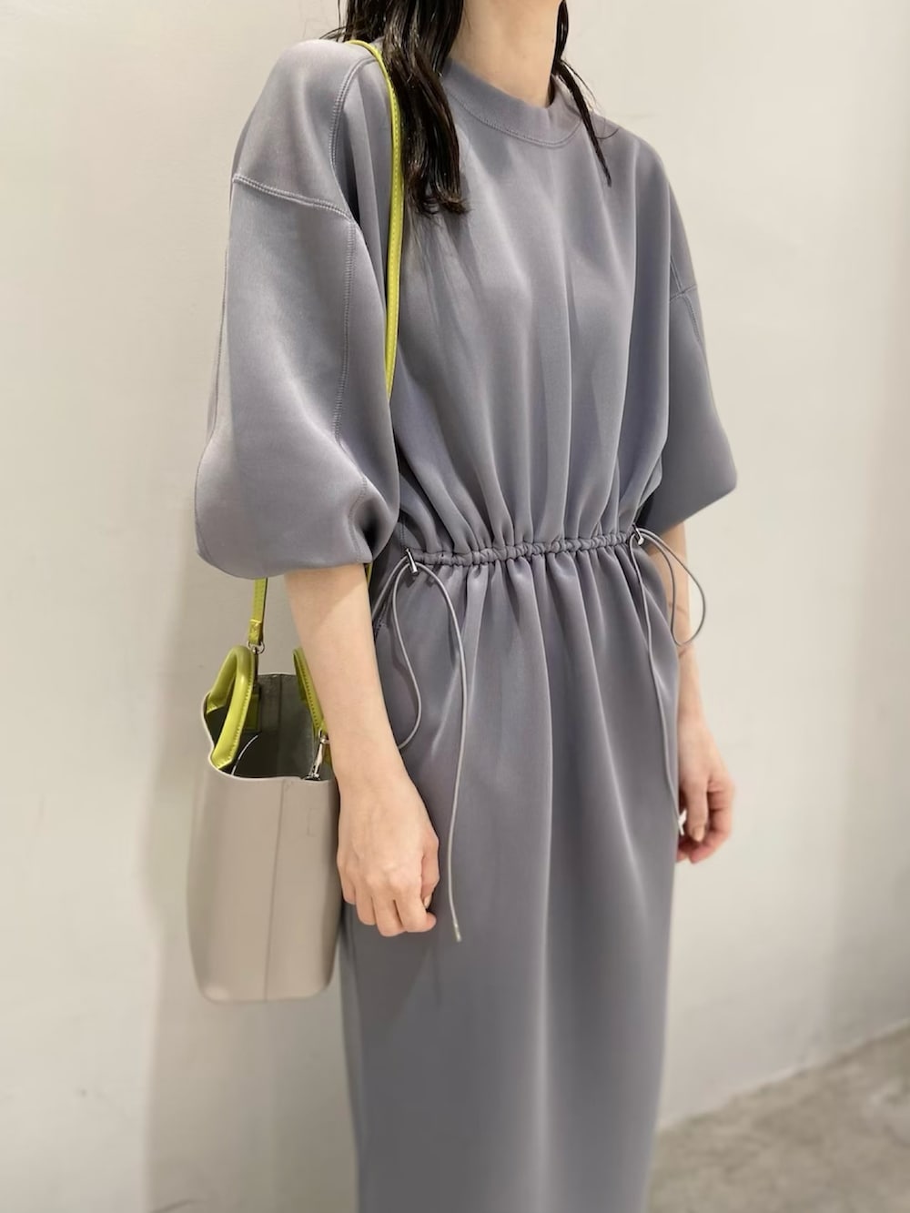 グレー系のワンピース、イエロー系のスニーカー、グレー系のショルダーバッグを着用したレディースの春コーディネートの5枚目の写真