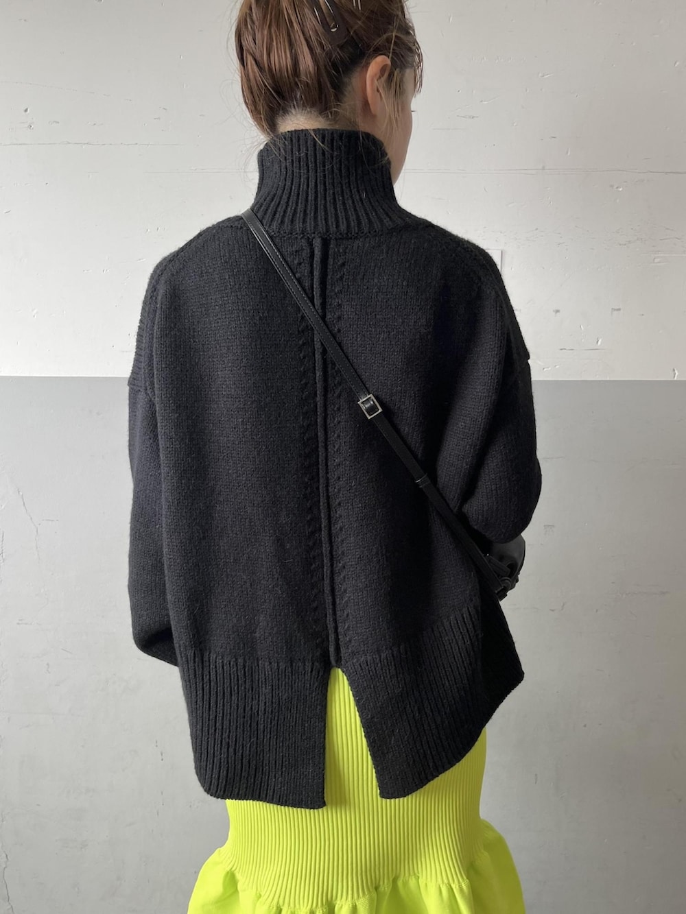 ブラック系のニット/セーター、グリーン系のスカート、ブラック系のブーツを着用したレディースの夏コーディネートの3枚目の写真