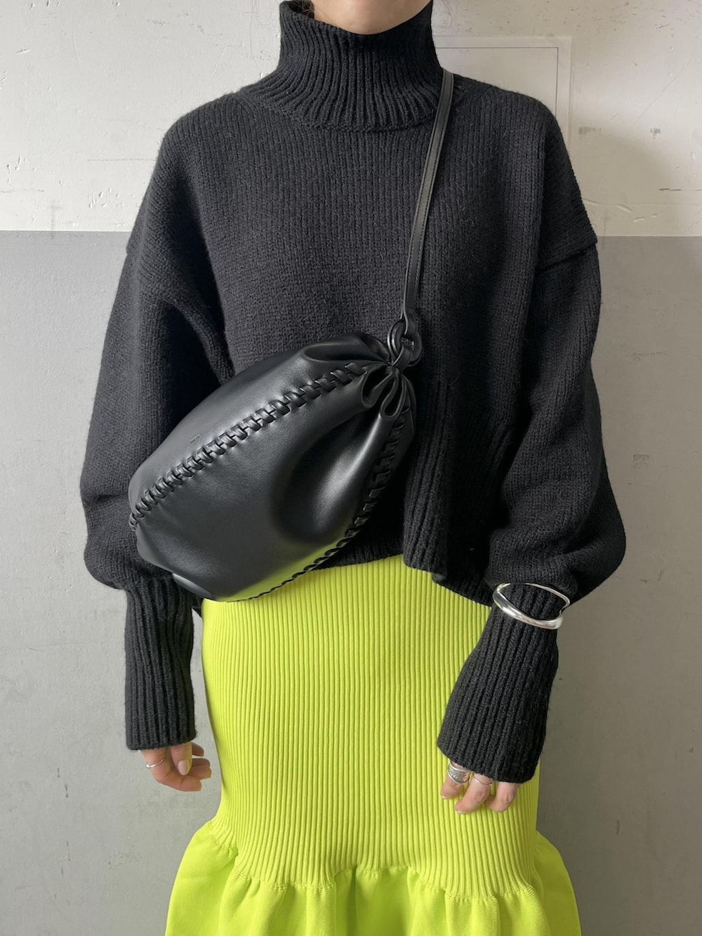 ブラック系のニット/セーター、グリーン系のスカート、ブラック系のブーツを着用したレディースの夏コーディネートの2枚目の写真