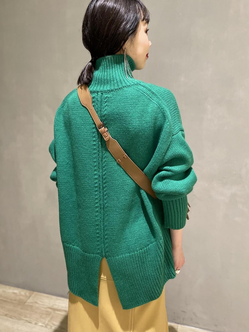 グリーン系のニット/セーター、ベージュ系のスカート、ブラック系のブーツを着用したレディースの夏コーディネートの3枚目の写真