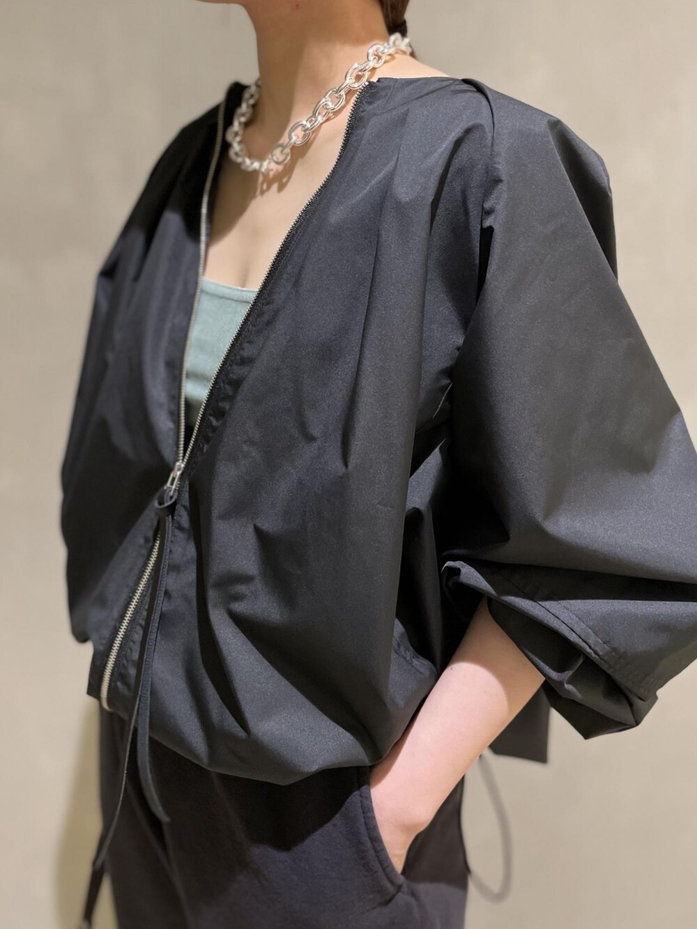 ブラック系のブルゾン、ブラック系のハンドバッグ、ブルー系のタンクトップを着用したレディースの冬コーディネートの4枚目の写真