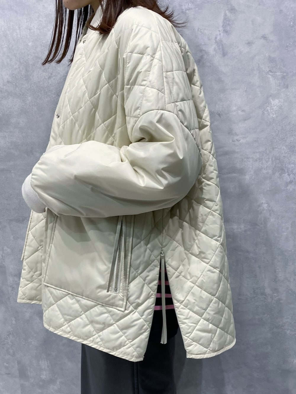 ホワイト系のブルゾン、ブラック系のスカート、グレー系のブーツを着用したレディースの秋コーディネートの4枚目の写真