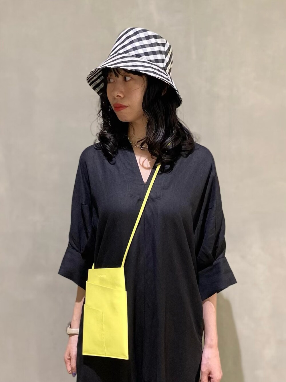 ブラック系のワンピース、イエロー系のショルダーバッグを着用したレディースの春コーディネートの3枚目の写真