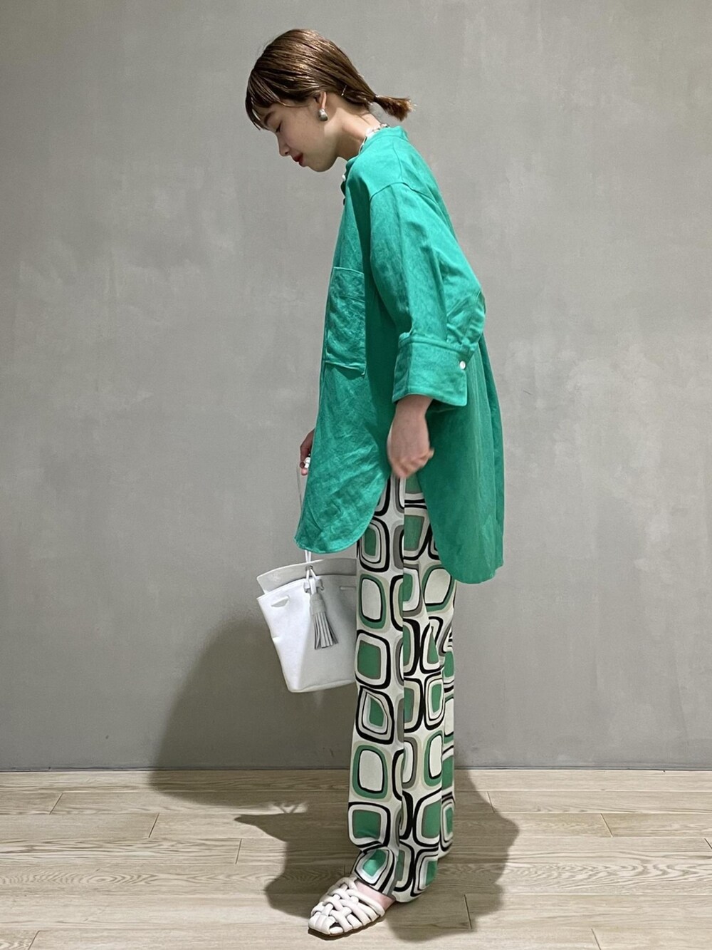 グリーン系のシャツ/ブラウス、ホワイト系のハンドバッグ、ホワイト系のシューズを着用したレディースの夏コーディネートの2枚目の写真