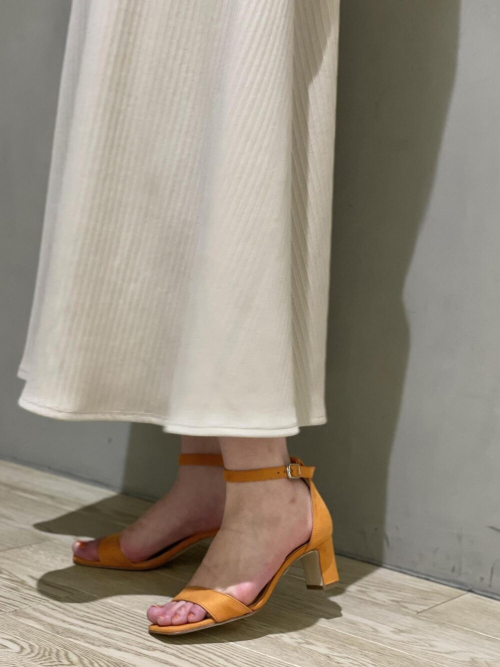 ホワイト系のテーラードジャケット、ベージュ系のワンピース、オレンジ系のサンダルを着用したレディースの春コーディネートの4枚目の写真