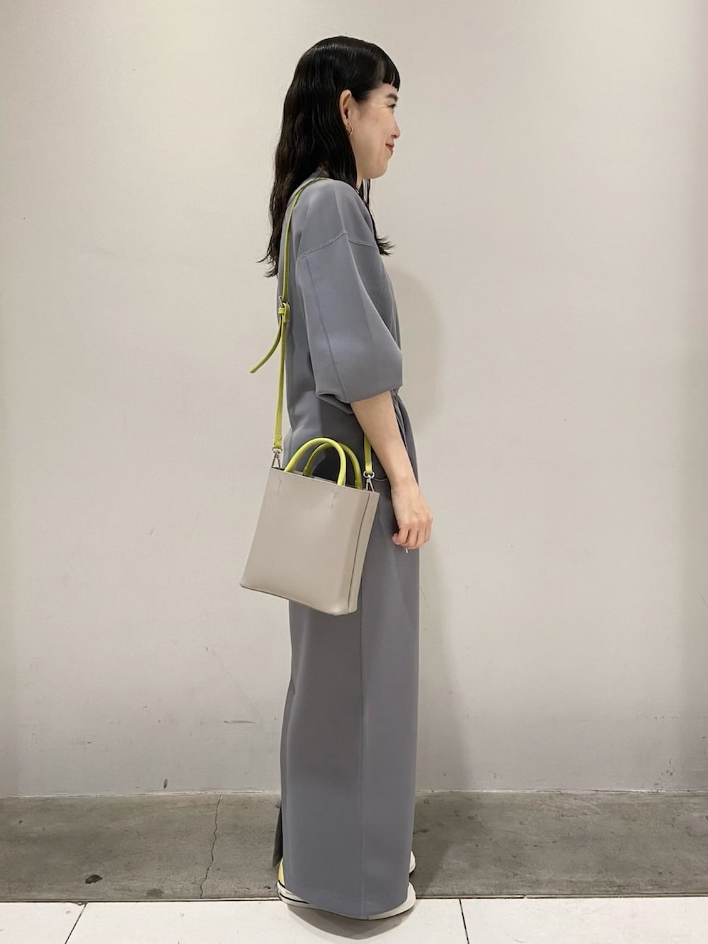 グレー系のワンピース、イエロー系のスニーカー、グレー系のショルダーバッグを着用したレディースの春コーディネートの3枚目の写真
