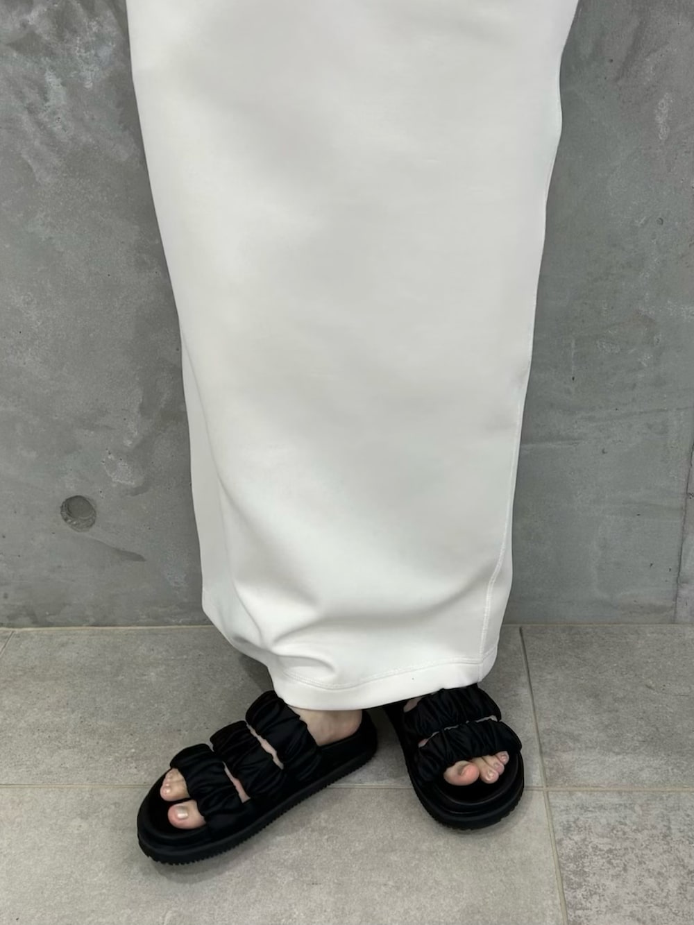 ホワイト系のワンピース、ブラック系のサンダルを着用したレディースの春コーディネートの5枚目の写真