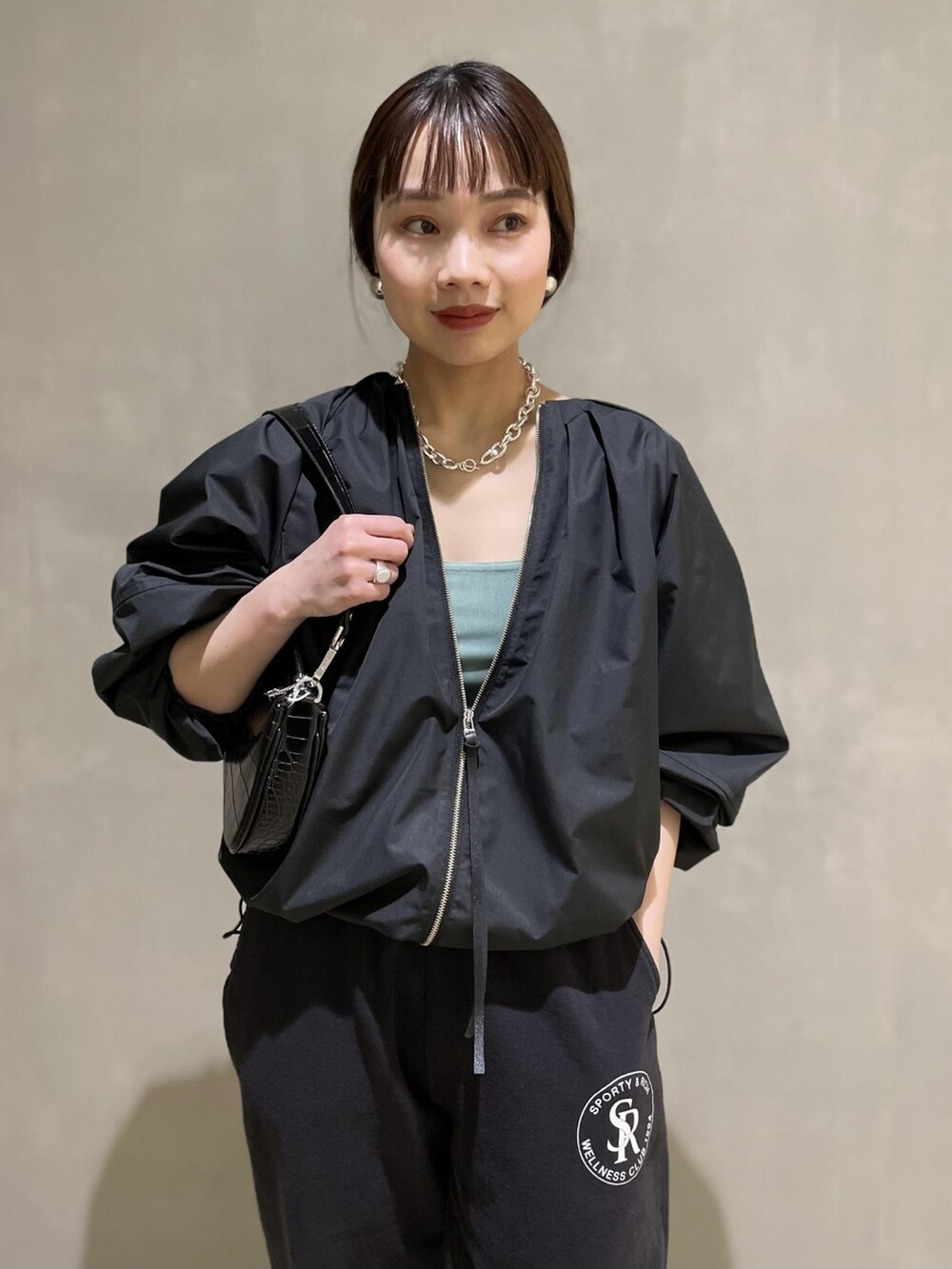 ブラック系のブルゾン、ブラック系のハンドバッグ、ブルー系のタンクトップを着用したレディースの冬コーディネートの2枚目の写真