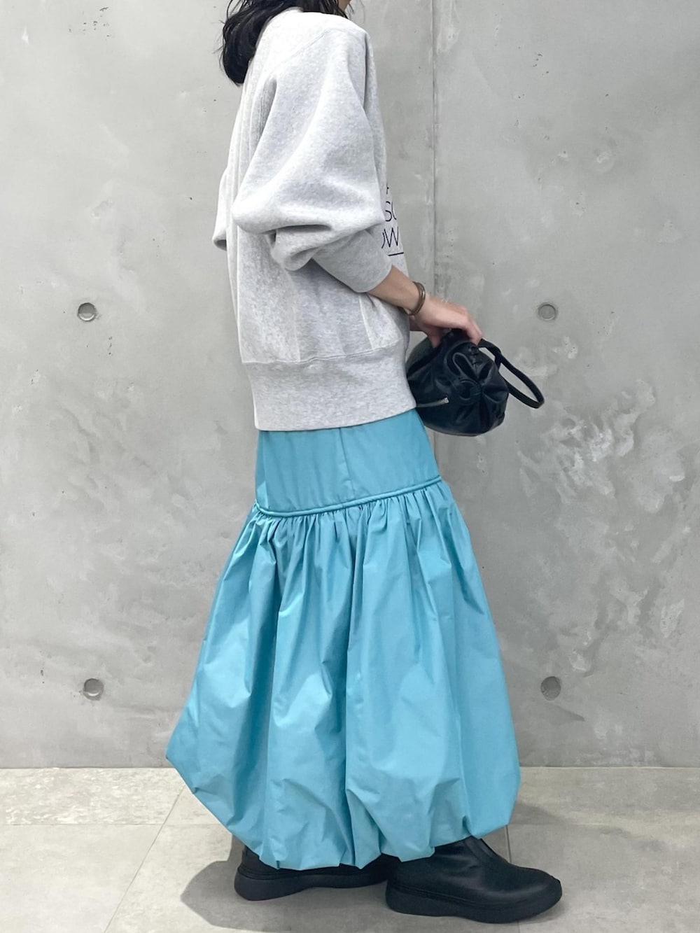 グレー系のスウェット、ブルー系のスカート、ブラック系のブーツを着用したレディースの夏コーディネートの2枚目の写真