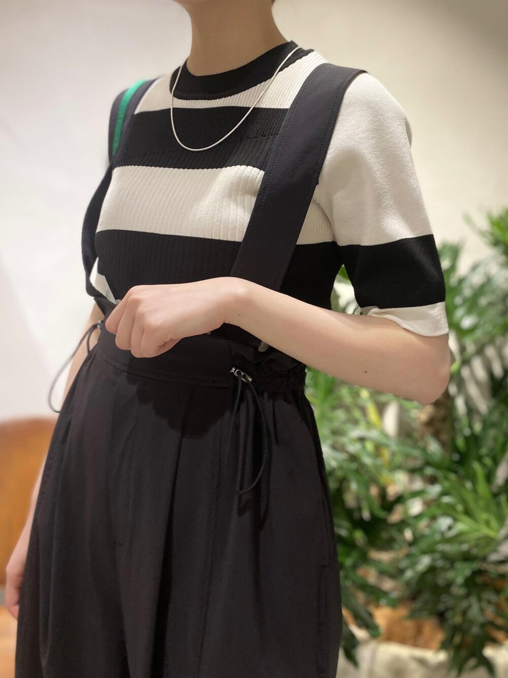 ブラック系のニット/セーター、ブラック系のサロペット/オーバーオール、グリーン系のハンドバッグを着用したレディースの春コーディネートの4枚目の写真