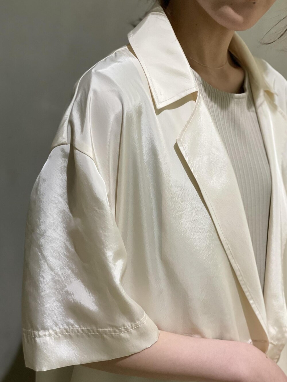 ホワイト系のテーラードジャケット、ベージュ系のワンピース、オレンジ系のサンダルを着用したレディースの春コーディネートの2枚目の写真