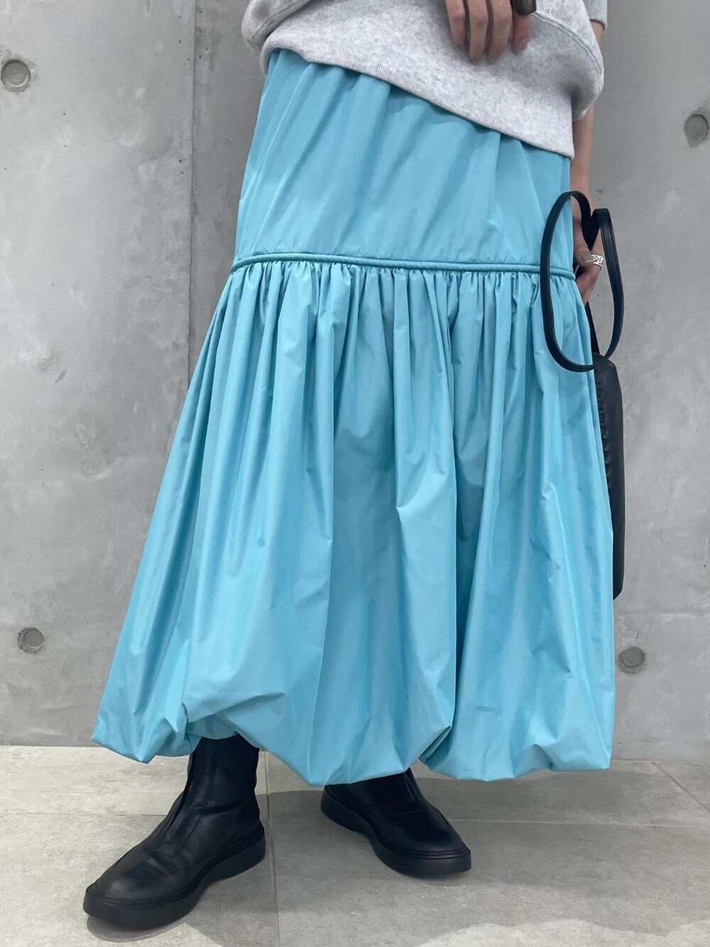 グレー系のスウェット、ブルー系のスカート、ブラック系のブーツを着用したレディースの夏コーディネートの4枚目の写真