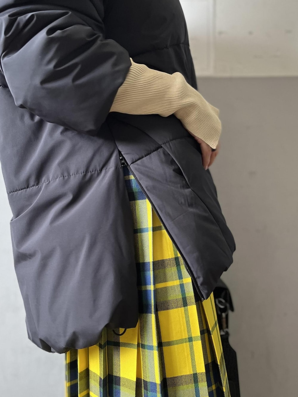 ブラック系のダウンジャケット/コート、ブラック系のショルダーバッグ、イエロー系のスカートを着用したレディースの秋コーディネートの5枚目の写真