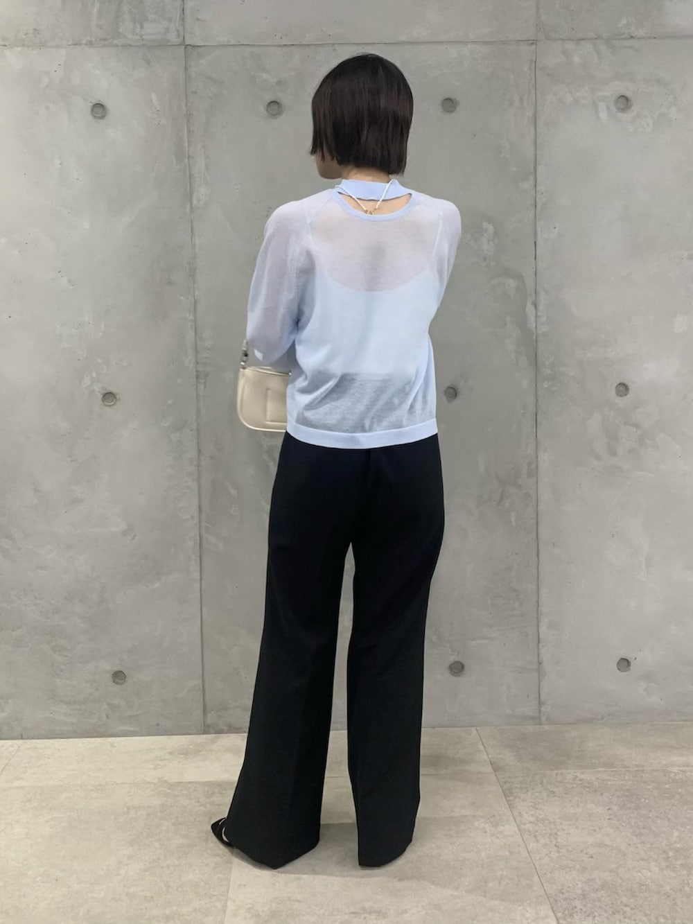 ブルー系のTシャツ/カットソー、ブラック系のスラックス、ホワイト系のショルダーバッグを着用したレディースの春コーディネートの4枚目の写真