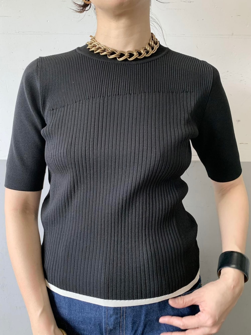 ブラック系のニット/セーター、パープル系のハンドバッグを着用したレディースの春コーディネートの3枚目の写真