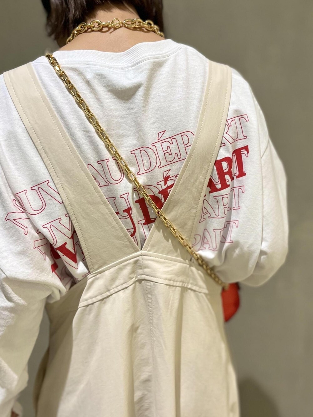 オレンジ系のショルダーバッグ、ホワイト系のジャンパースカート、ブラック系のブーツを着用したレディースの春コーディネートの4枚目の写真