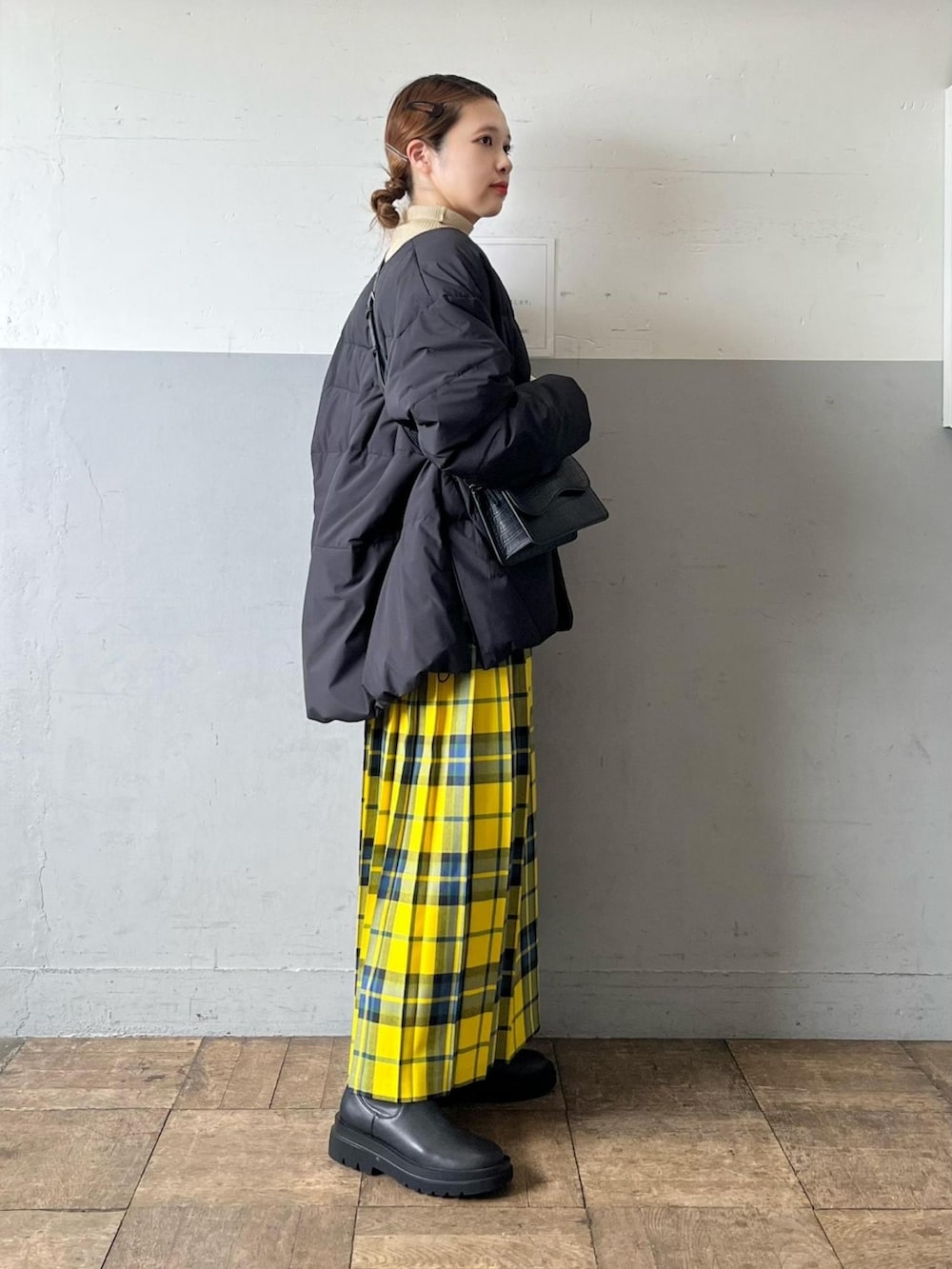 ブラック系のダウンジャケット/コート、ブラック系のショルダーバッグ、イエロー系のスカートを着用したレディースの秋コーディネートの2枚目の写真