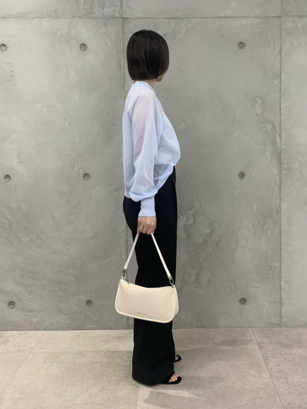 ブルー系のTシャツ/カットソー、ブラック系のスラックス、ホワイト系のショルダーバッグを着用したレディースの春コーディネートの3枚目の写真