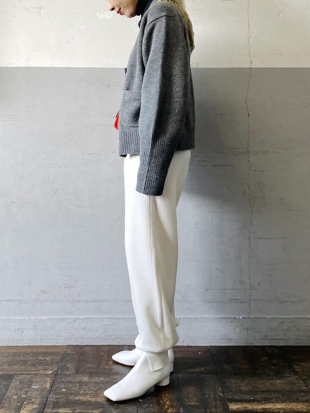 オレンジ系のショルダーバッグ、グレー系のカーディガン/ボレロ、ホワイト系のその他パンツを着用したレディースの冬コーディネートの3枚目の写真