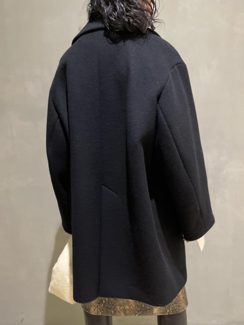 ブラック系のその他アウター、ホワイト系のニット/セーター、ホワイト系のハンドバッグを着用したレディースの冬コーディネートの5枚目の写真