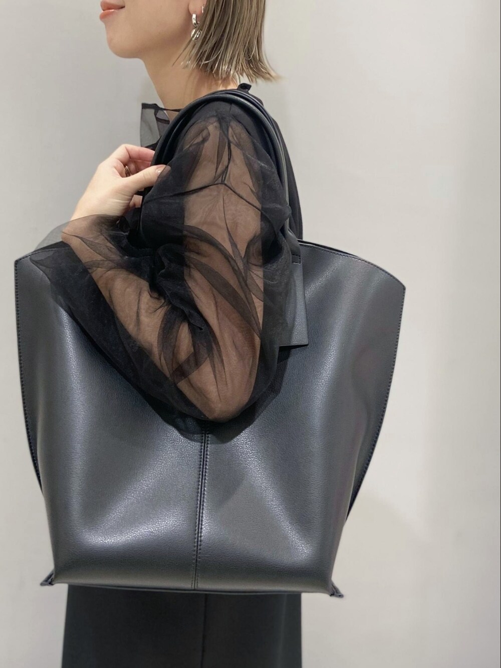 ブラック系のワンピース、ブラック系のTシャツ/カットソー、ブラック系のトートバッグを着用したレディースの春コーディネートの5枚目の写真