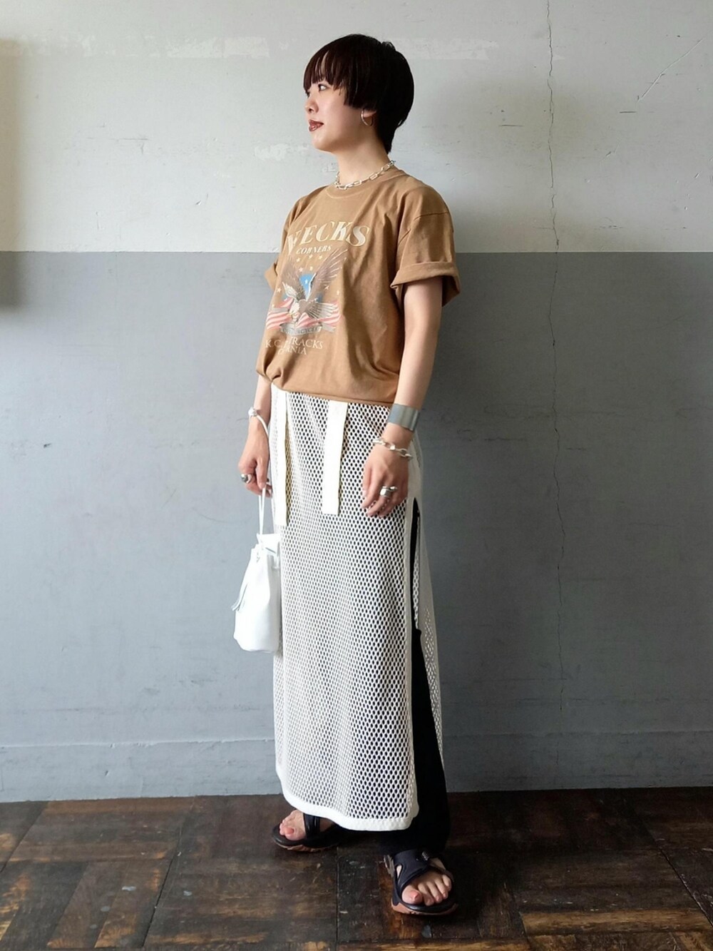 ベージュ系のTシャツ/カットソー、ホワイト系のワンピース、ホワイト系のハンドバッグを着用したレディースの夏コーディネートの2枚目の写真