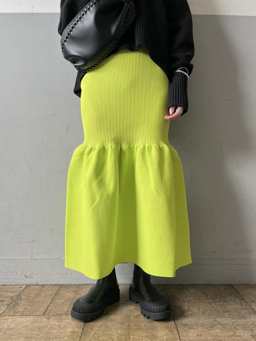 ブラック系のニット/セーター、グリーン系のスカート、ブラック系のブーツを着用したレディースの夏コーディネートの4枚目の写真