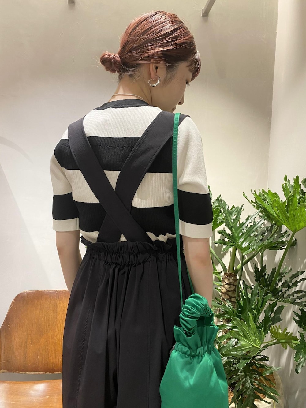 ブラック系のニット/セーター、ブラック系のサロペット/オーバーオール、グリーン系のハンドバッグを着用したレディースの春コーディネートの5枚目の写真