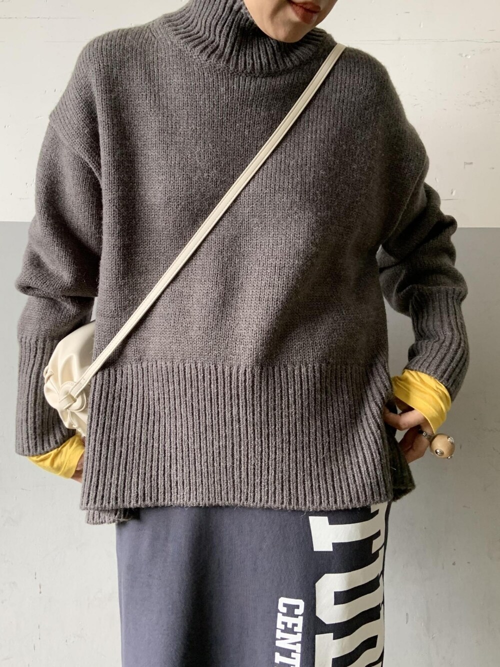 グレー系のニット/セーター、イエロー系のTシャツ/カットソー、ホワイト系のブーツを着用したレディースの夏コーディネートの3枚目の写真