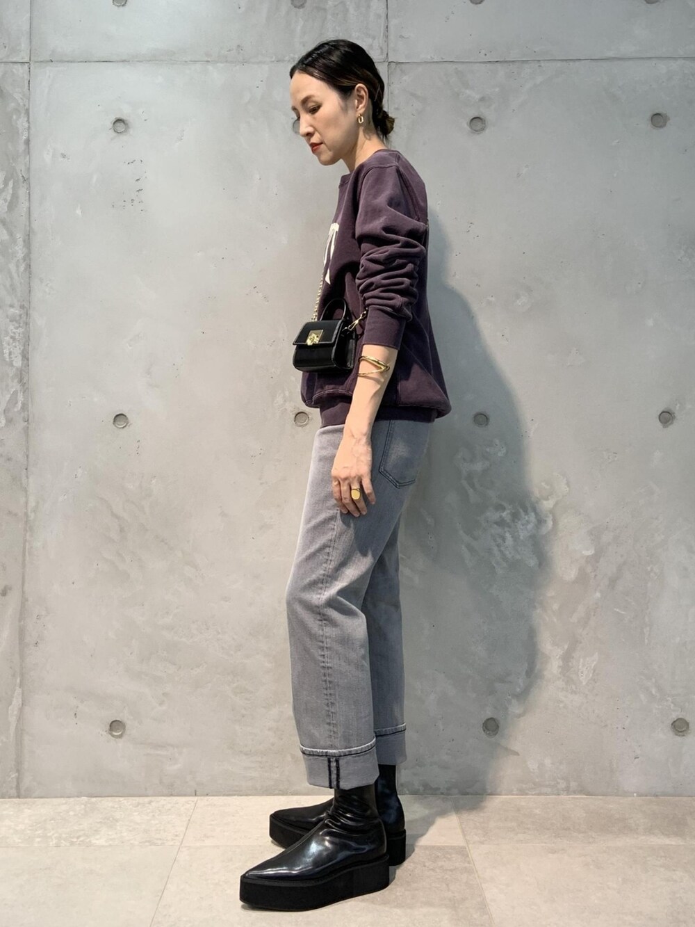 パープル系のスウェット、ブラック系のショルダーバッグ、グレー系のデニムパンツを着用したレディースの夏コーディネートの2枚目の写真