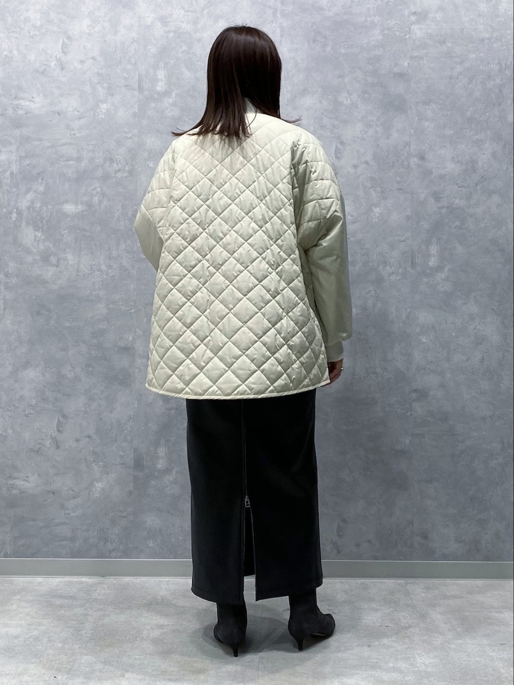 ホワイト系のブルゾン、ブラック系のスカート、グレー系のブーツを着用したレディースの秋コーディネートの3枚目の写真